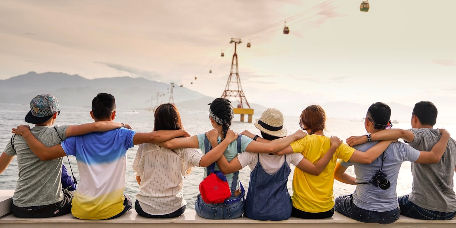 Friends, arms around each other, looking out over a bay